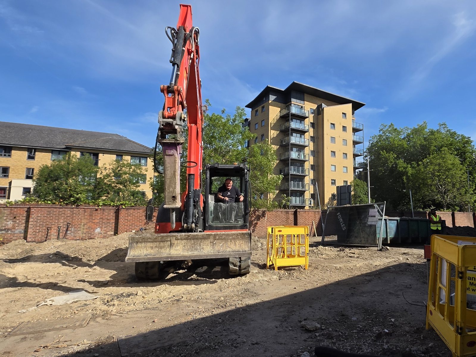 Excavator with a pecker attachment working on a site strip